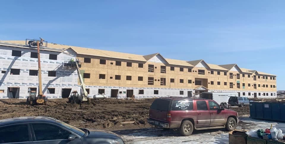 Three-story apartment complex under construction with a boom truck on site