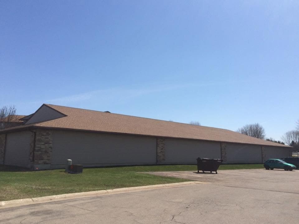 Long single-story commercial building under a new tan shingle roof