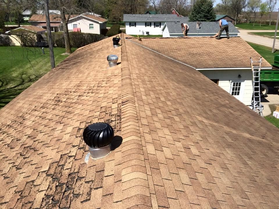 Roof with a turbine vent in place while the crew works the next building over