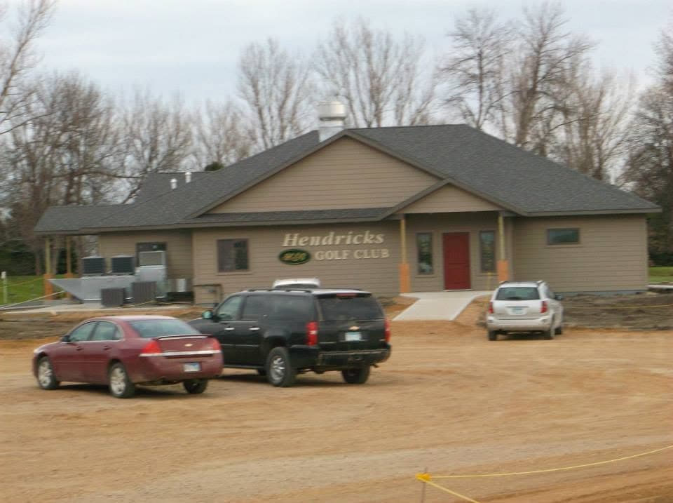 The Hendricks Golf Club clubhouse with its new roof finished, vehicles parked on the still-unfinished lot