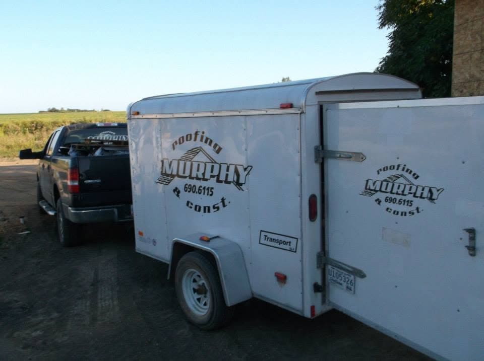 The Murphy Roofing and Construction trailer hitched to a pickup, parked beside an open farm field