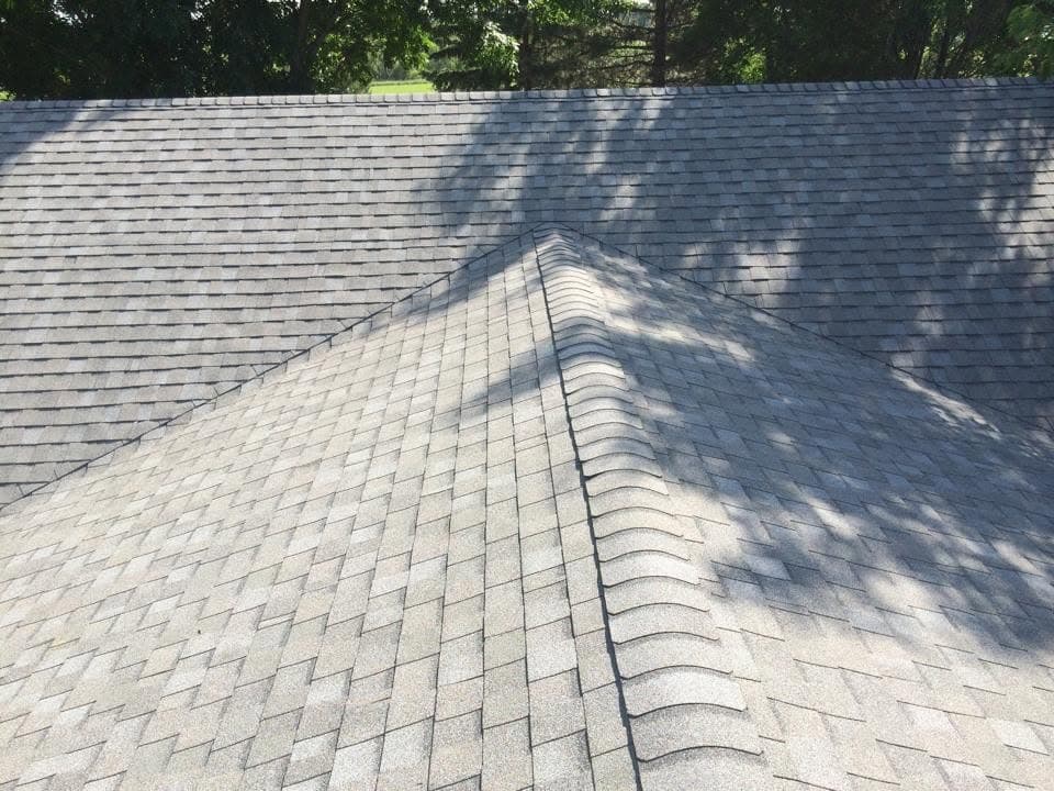 Crisp new hip ridge line meeting at the peak of a shingle roof
