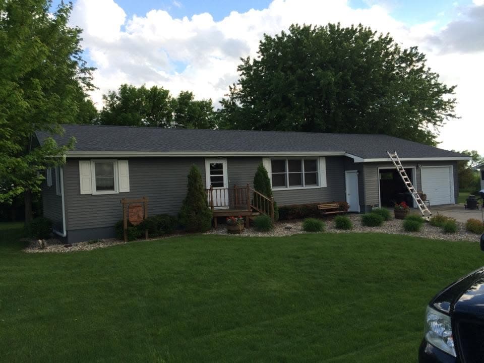 Gray house on a green lawn with its roof finished