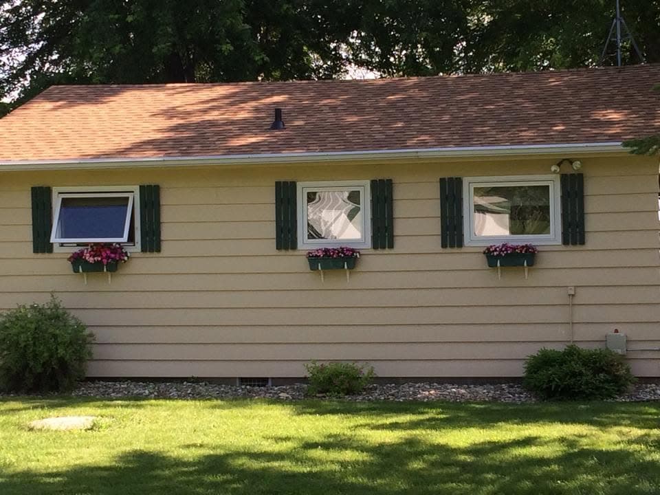Single-story home with window flower boxes under a new brown shingle roof
