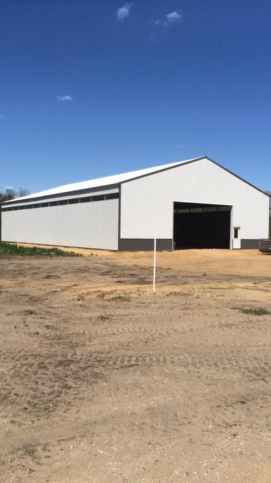 White steel pole barn with a telehandler working the site