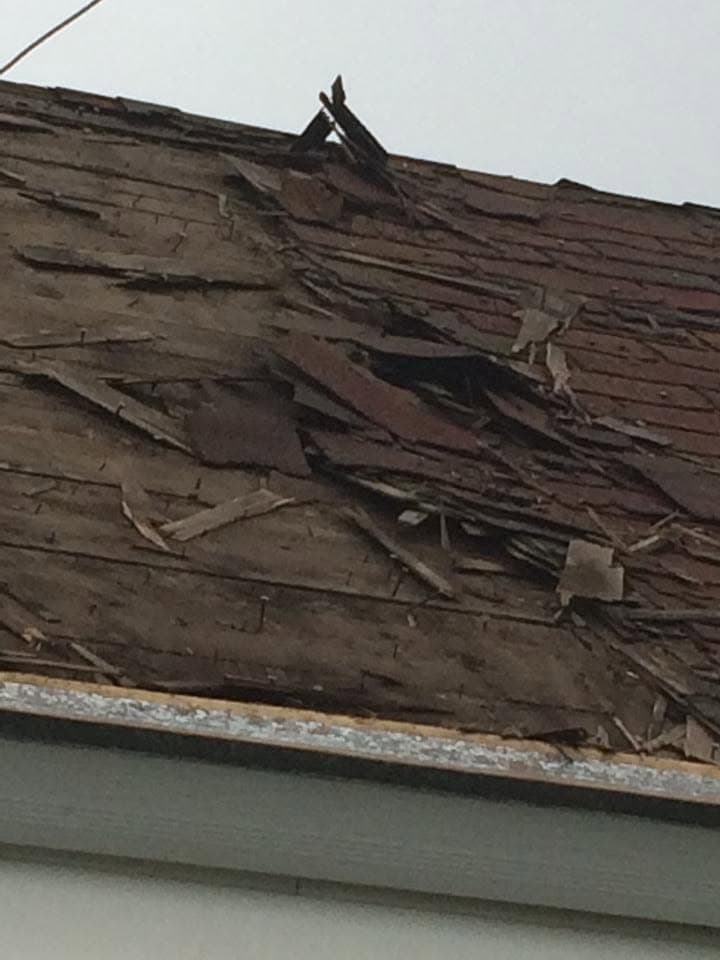 Weathered old roofing stripped back to brittle layers during tear-off