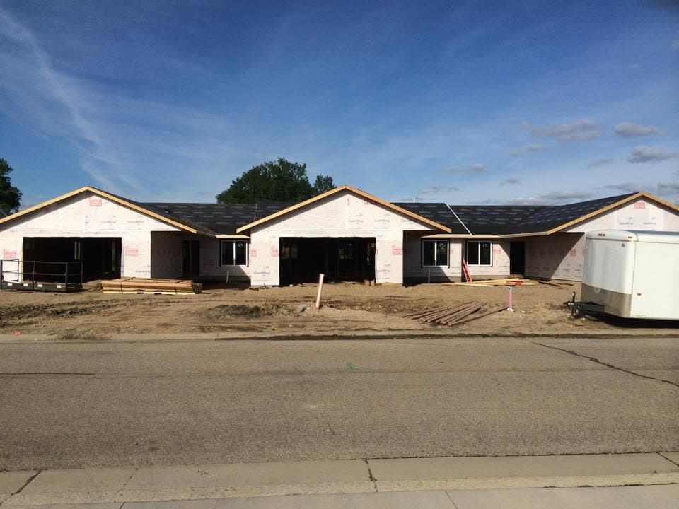 Row of new townhomes under construction with roofing material staged